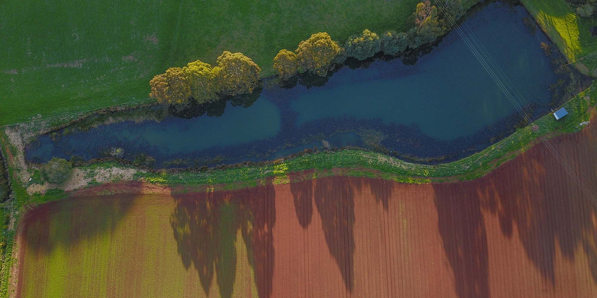 Bird's eye view of river running next to paddock
