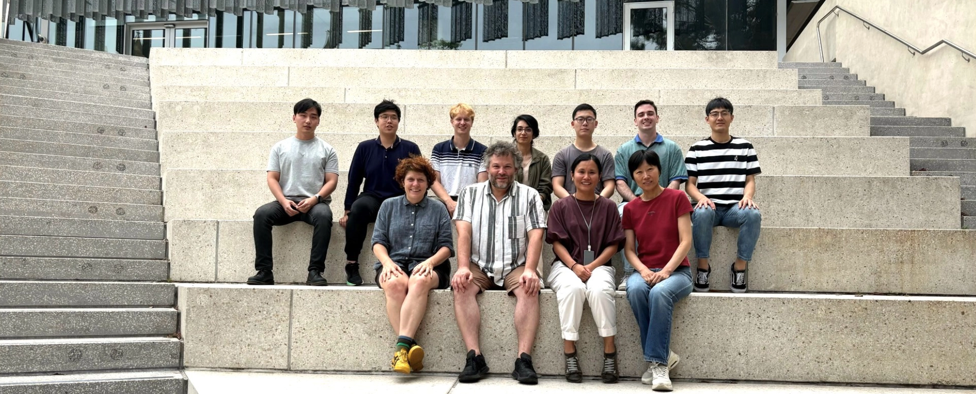 Research group members sitting on steps outside.