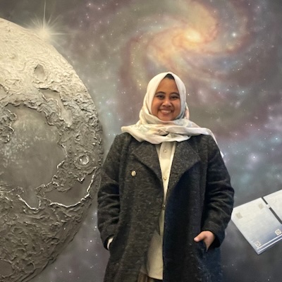 Amatul Firdausya Nur, standing in front of a mural of space
