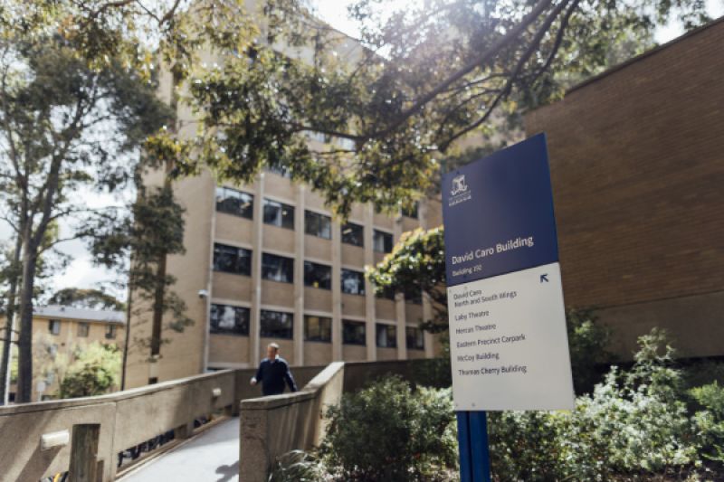 Man walking down a ramp next to a sign saying 'David Caro Building'