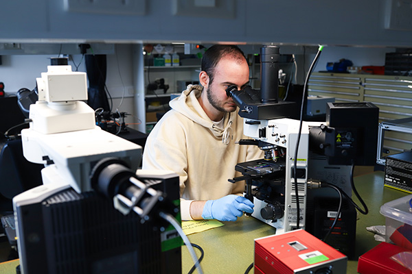 Man in lab looks into microscrope
